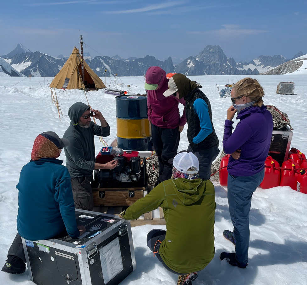 6 researchers in snow gear gather around the camp at Mt Waddington